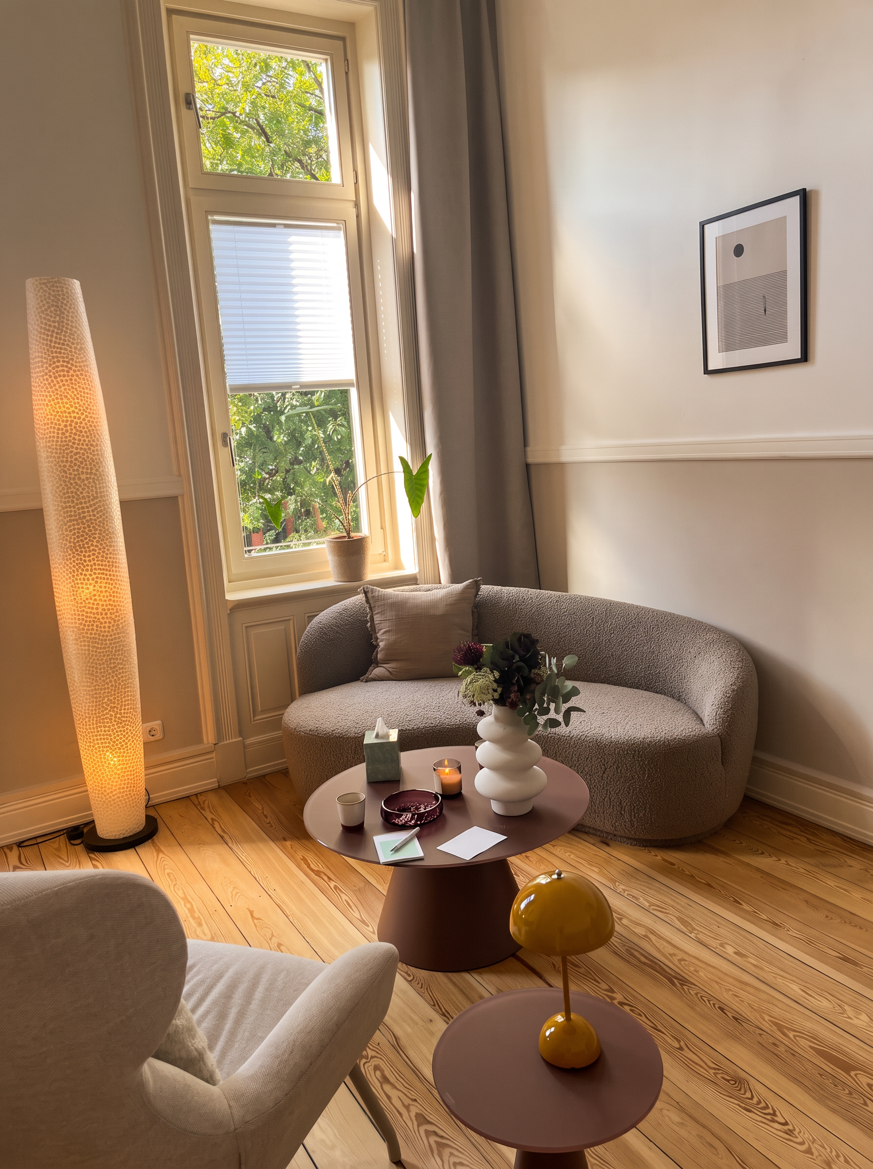 Behandlungsraum mit rundem Bouclé-Sofa, Kerze und Blumen